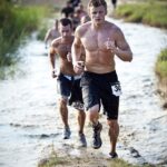 Men running through a muddy obstacle course