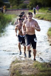 Men running through a muddy obstacle course