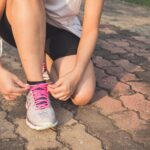 A girl lacing up some running shoes